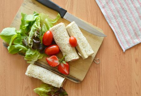 bread roll and salad on wooden chop blockの写真素材