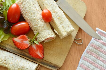 bread roll and salad on wooden chop plateの写真素材