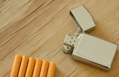 silver lighter with cigarette on wooden boardの写真素材