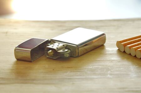 silver lighter with cigarette on wooden boardの写真素材