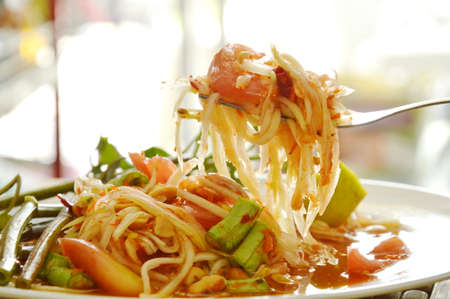 Somtum Thai green papaya salad tasted spicy sour and sweet on forkの写真素材