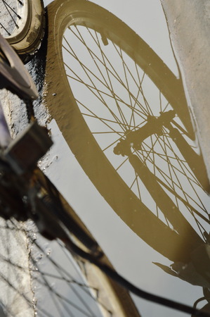 bicycle wheel reflection in water flood on street after rainingの写真素材