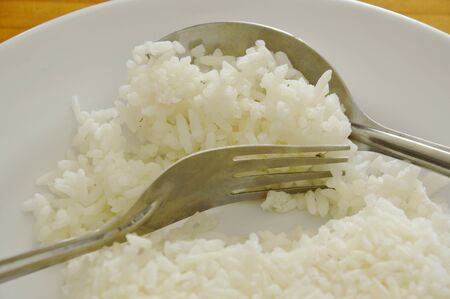 rice scooping by spoon and fork from plate for eatingの写真素材