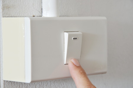 human finger closed toggle switch in plastic box on wallの写真素材