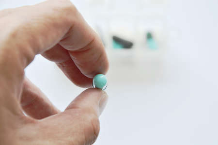 medicine capsule picking in human finger with drug box backgroundの写真素材