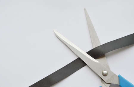 scissors blade cutting black cloth ribbon on white backgroundの写真素材