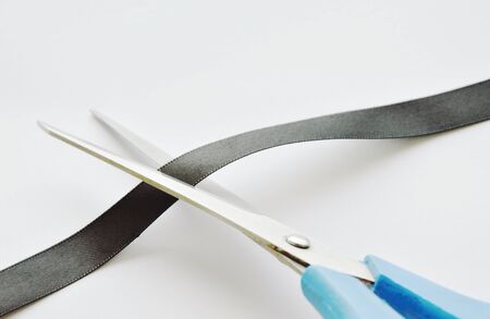 scissors blade cutting black cloth ribbon on white backgroundの写真素材