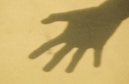 shadow of opened hand on old cement wallの写真素材