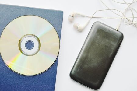book and CD- rom with earphones connect in smartphone on white backgroundの写真素材