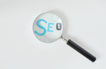 magnifying glass view on SEO paper cut letter on white backgroundの写真素材