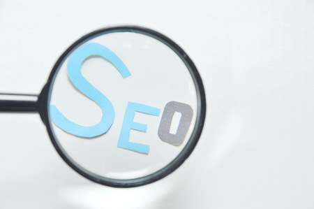 magnifying glass view on SEO paper cut letter on white backgroundの写真素材