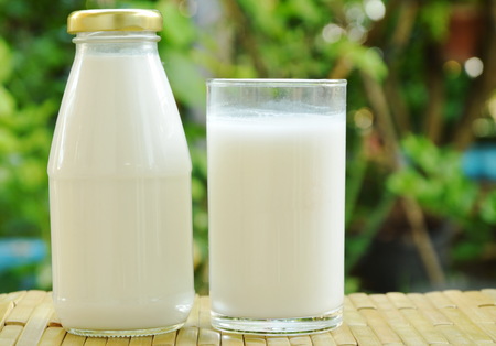 bottle and glass of milk on bamboo mat in gardenの写真素材
