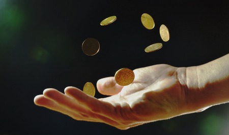 coin floating on human hand in black backgroundの写真素材