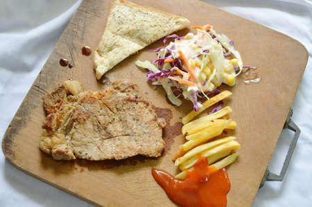 pepper pork steak with French fried and salad on wooden chop blockの写真素材