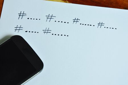 hashtag symbol for grouping content in social media write on paper and smartphoneの写真素材