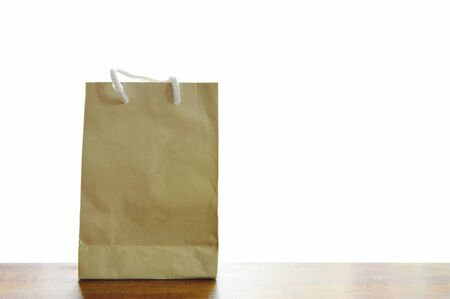 brown paper bag with cloth handle on wooden board in white backgroundの写真素材