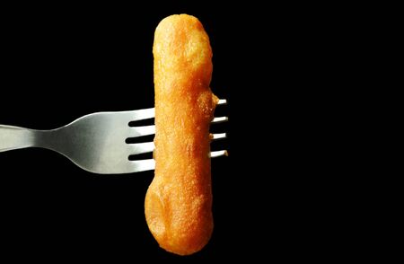 fried chicken sausage stabbing in fork on black backgroundの写真素材