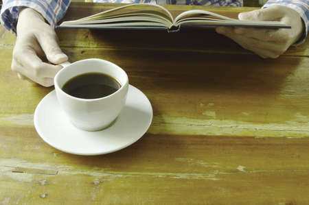 hand open book and read while drinking black coffeeの写真素材