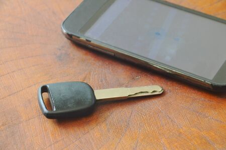 car key and smart phone opened map on wooden tableの写真素材