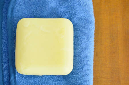 yellow soap and blue towel on wooden tableの写真素材