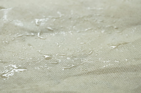 drop of water rolling on artificial fabric bagの写真素材