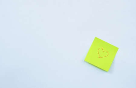 yellow paper note drawing red heart shape stick on white backgroundの写真素材