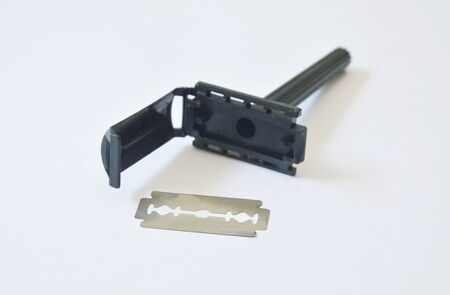 Black plastic shaver and razor blade on white background