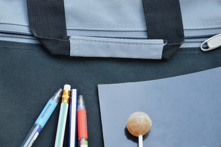 pen pencil and book with lollipop on black fabric briefcaseの写真素材