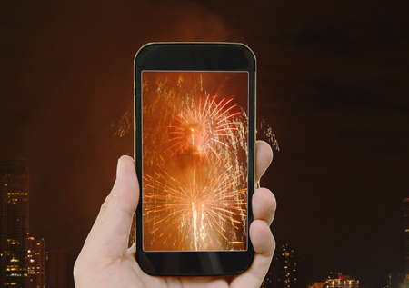 mobile phone holding in human hand with fireworks on screen
