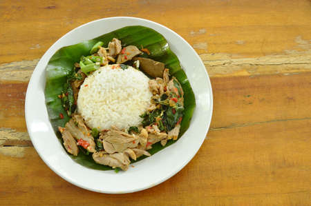 spicy fried duck meat with basil leaf and rice on fresh banana leafの写真素材