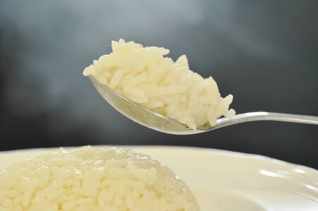 plain rice scooping on silver spoon with smoke floatingの写真素材