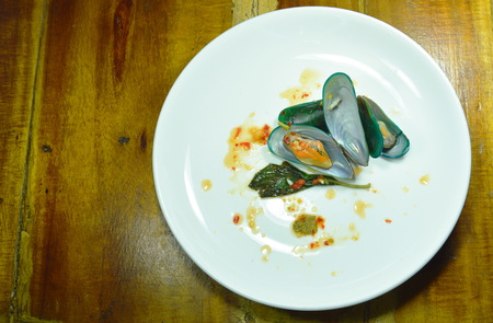 steamed mussel dressing with spicy sauce on white plate