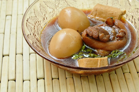 boiled egg with pork leg in herb brown soup on glass bowlの写真素材