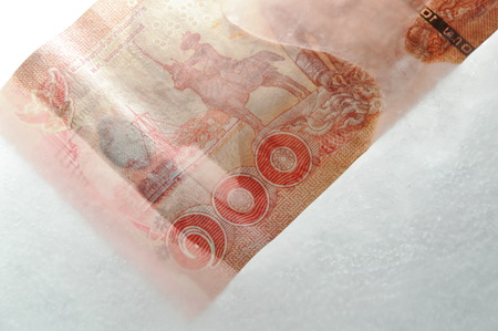 Thai banknote freezing in ice on plastic trayの写真素材