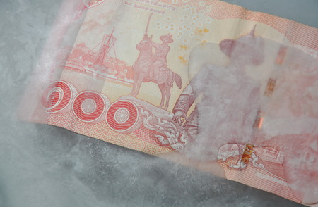 Thai banknote freezing in ice on plastic tray
