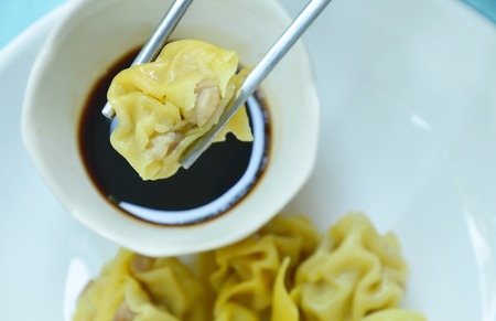 Chinese pork dumpling picking in stainless chopsticks on soy sauce cupの写真素材