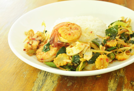 Spicy fried prawn and squid with herb on riceの写真素材