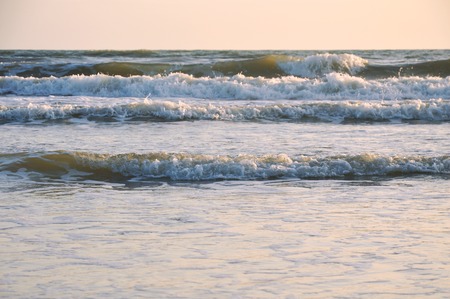 landscape of sea and water surf to beach in sunsetの写真素材