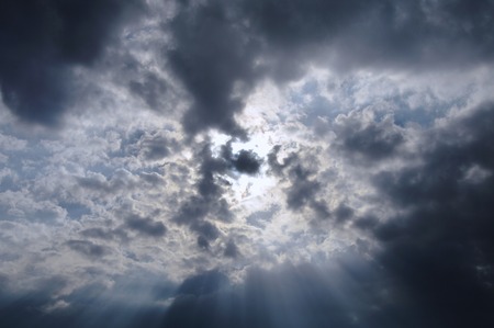 sunbeam spreading light through dark cloud on sky