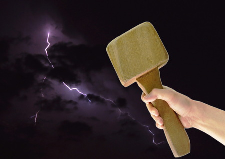 hand holding big wooden hammer on thunderbolt in night backgroundの写真素材