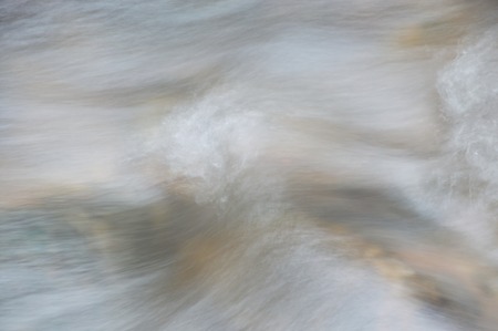 Close up of blurry water flowing on river in forest