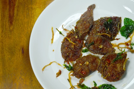 spicy stir fried crispy catfish curry with herb on plateの写真素材