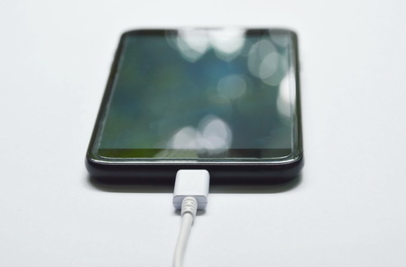 mobile phone stabbing in rechargeable battery with rubble cable on white background