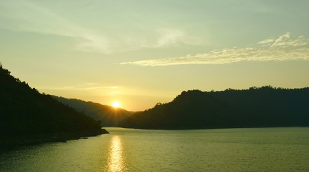 sunrise behind mountain on river in Thailand