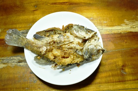 deep fried salty bass fish with garlic on plate