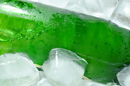 green beer bottle on ice in plastic trayの写真素材