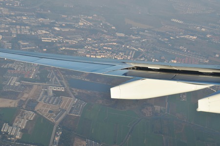 plane wing  through window frame and city view on ground