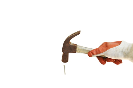 hand wearing safety glove holding old iron hammer smashing on nail in white backgroundの素材 [FY310120486468]