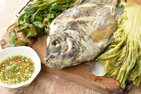 steamed mango fish with vegetable dipping spicy sauce on wooden chop blockの写真素材