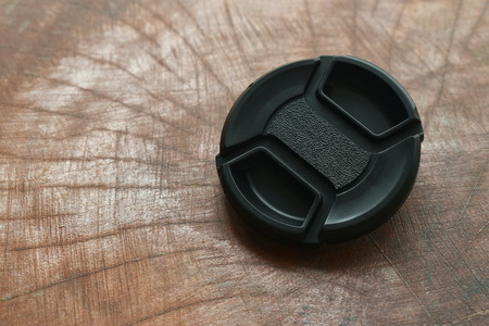 black camera lens cap for protection on wooden board